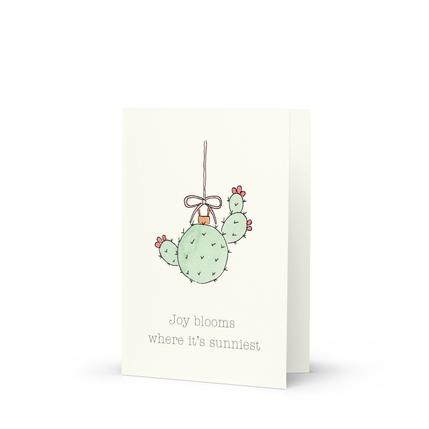 Card with a cactus ornament illustration and text on a white background that reads "Joy blooms where it's sunniest"