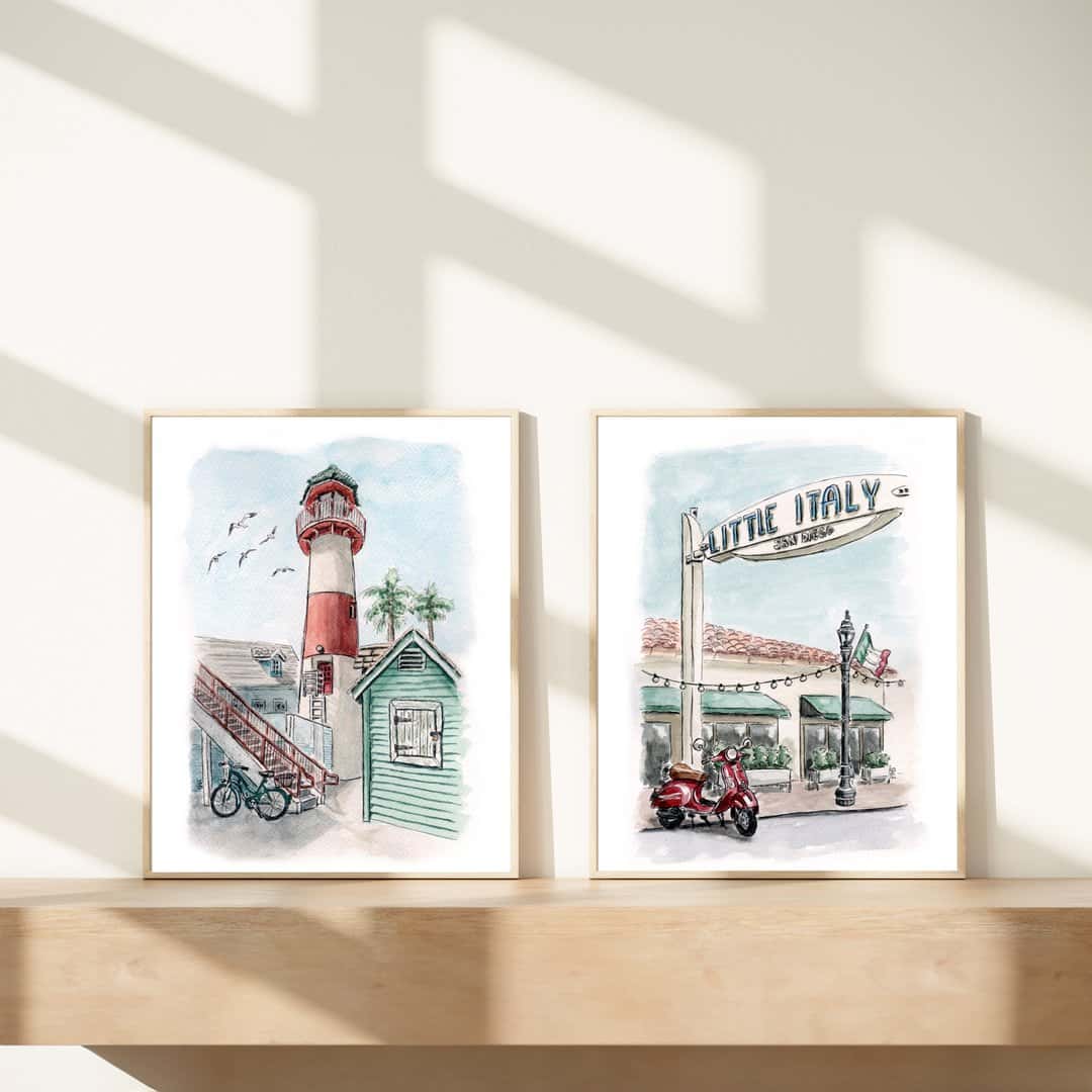 Two framed watercolor paintings featuring a red-and-white coastal lighthouse with a small green building and a bike, and the iconic 'Little Italy' sign in San Diego with a red Vespa parked beneath string lights. Perfect for coastal, Southern California and travel-inspired decor by Swil Arts.