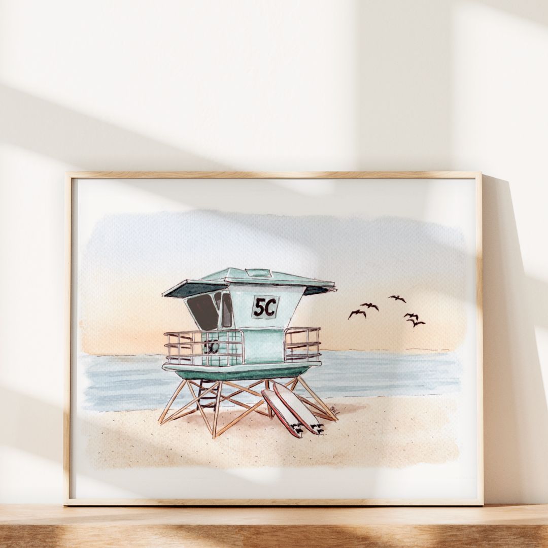 Guardian of the Shores by Swil Arts features a framed watercolor of Southern California’s “5C” lifeguard tower on a sandy beach with waves and five birds, displayed as coastal wall art basking in sunlight.