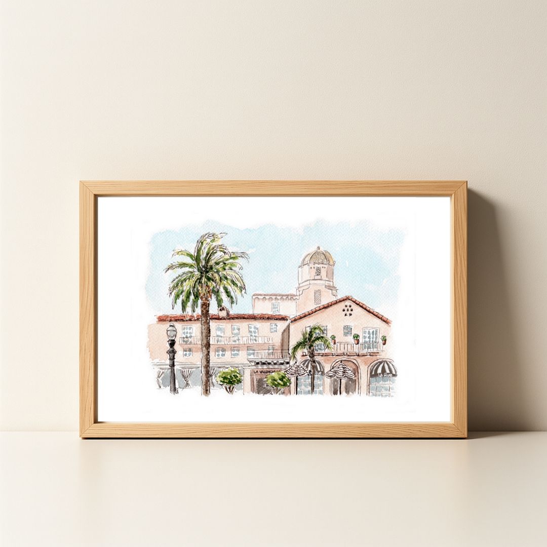 Watercolor painting of a pink building with palm trees in a wooden frame.