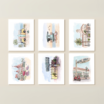 The Southern California Greeting Card Box Set - Watercolor Art features six cards with beach and city scenes, including buildings, a pier, a lifeguard tower, and a vintage camper van—perfect for fans of SoCal-inspired artwork.