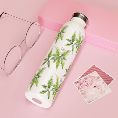 White stainless steel water bottle with a repeating starflower flower watercolor design, placed on a pink background with glasses and floral photographs.