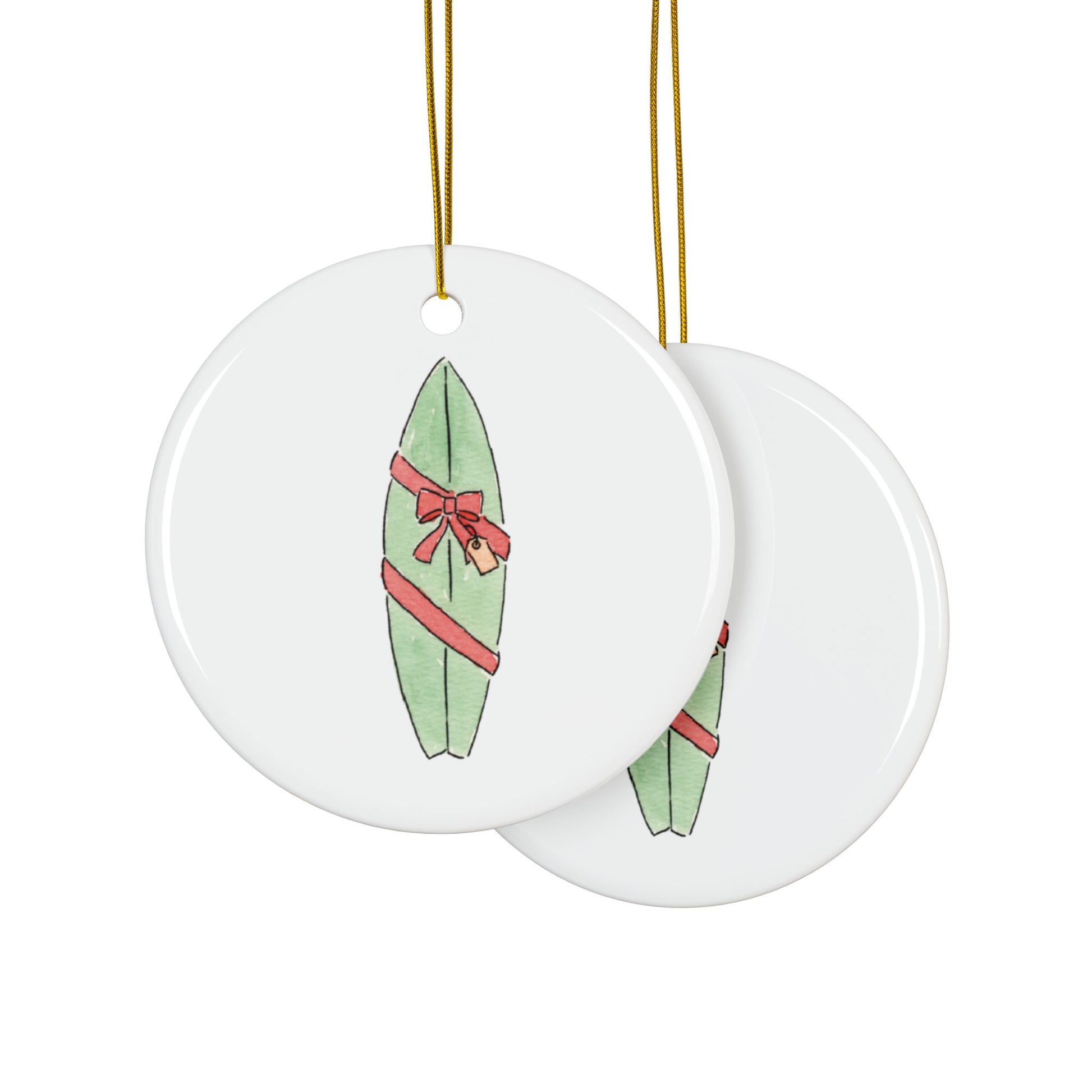 Two round ceramic ornaments with green surfboards and red bows on a white background
