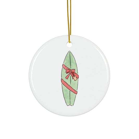 Round ceramic ornament with a green surfboard wrapped as a gift design on a white background