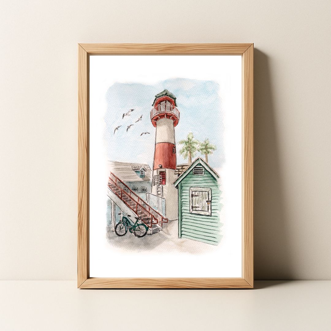 Framed watercolor painting of a red and white lighthouse, a beach shack, a bicycle, and flying birds.