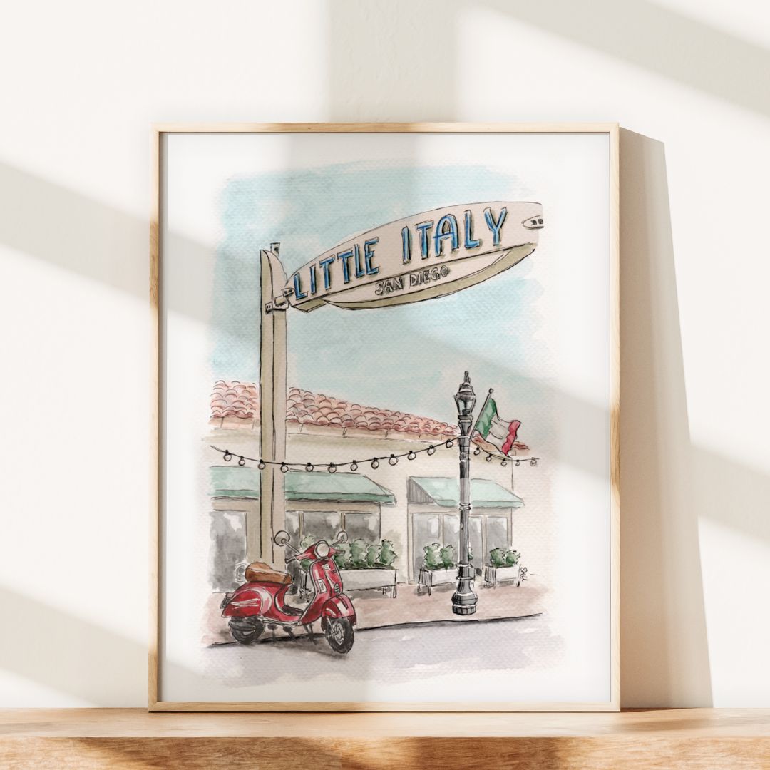 Framed watercolor painting of a Little Italy, San Diego street scene with a scooter, sign, and Italian flag.
