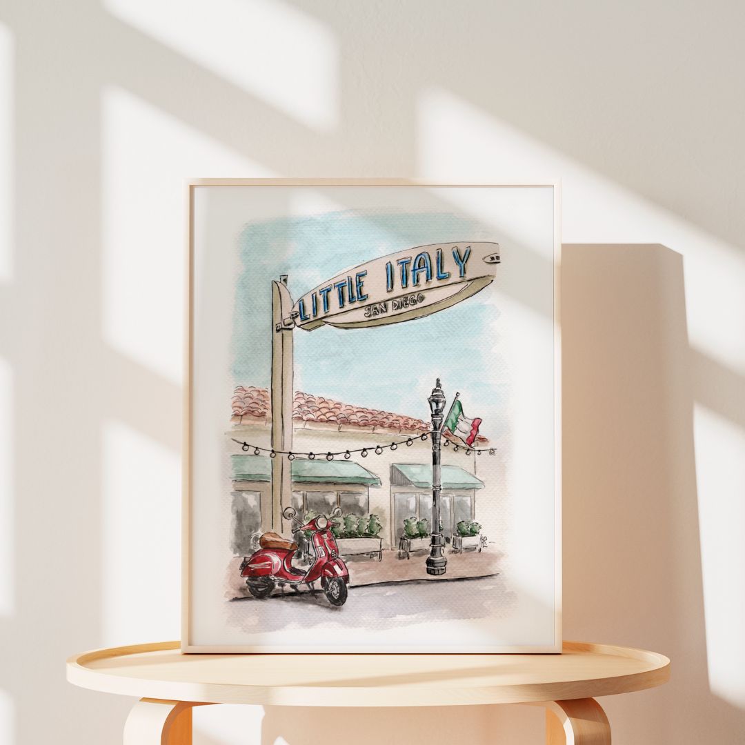 Framed watercolor painting of a Little Italy, San Diego street scene with a scooter, sign, and Italian flag.