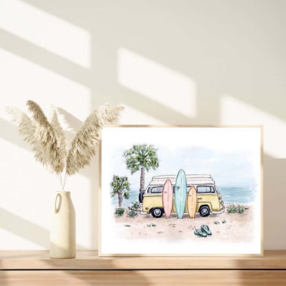 Framed watercolor print of a yellow vintage van with surfboards on a beach, styled with pampas grass in a minimalist decor setup. Palm trees and ocean view in the background. Ideal surf and beach-themed wall art for coastal home decor
