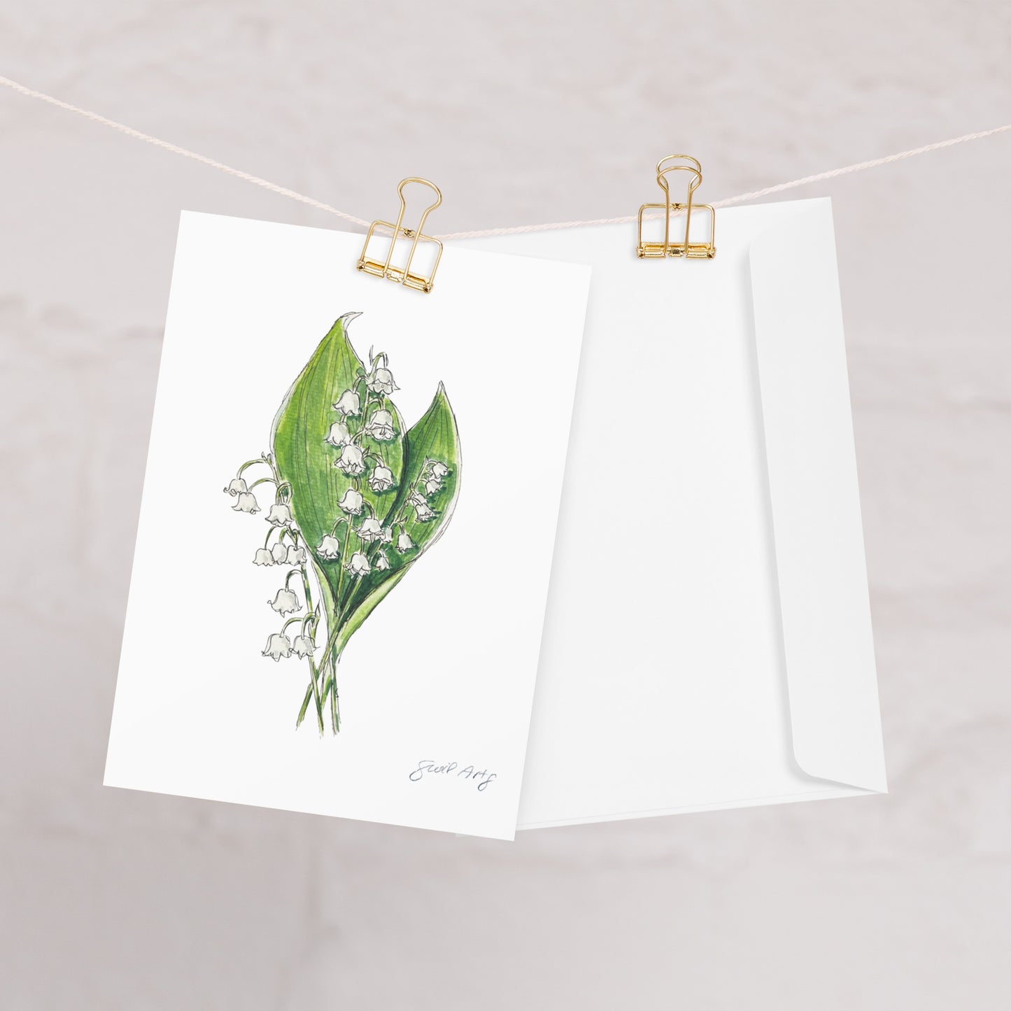 Lily of the Valley flower greeting card with a watercolor and ink botanical illustration, clipped to a string with a gold binder clip. Includes a matching white envelope. Perfect for nature lovers, special occasions, and handwritten notes.