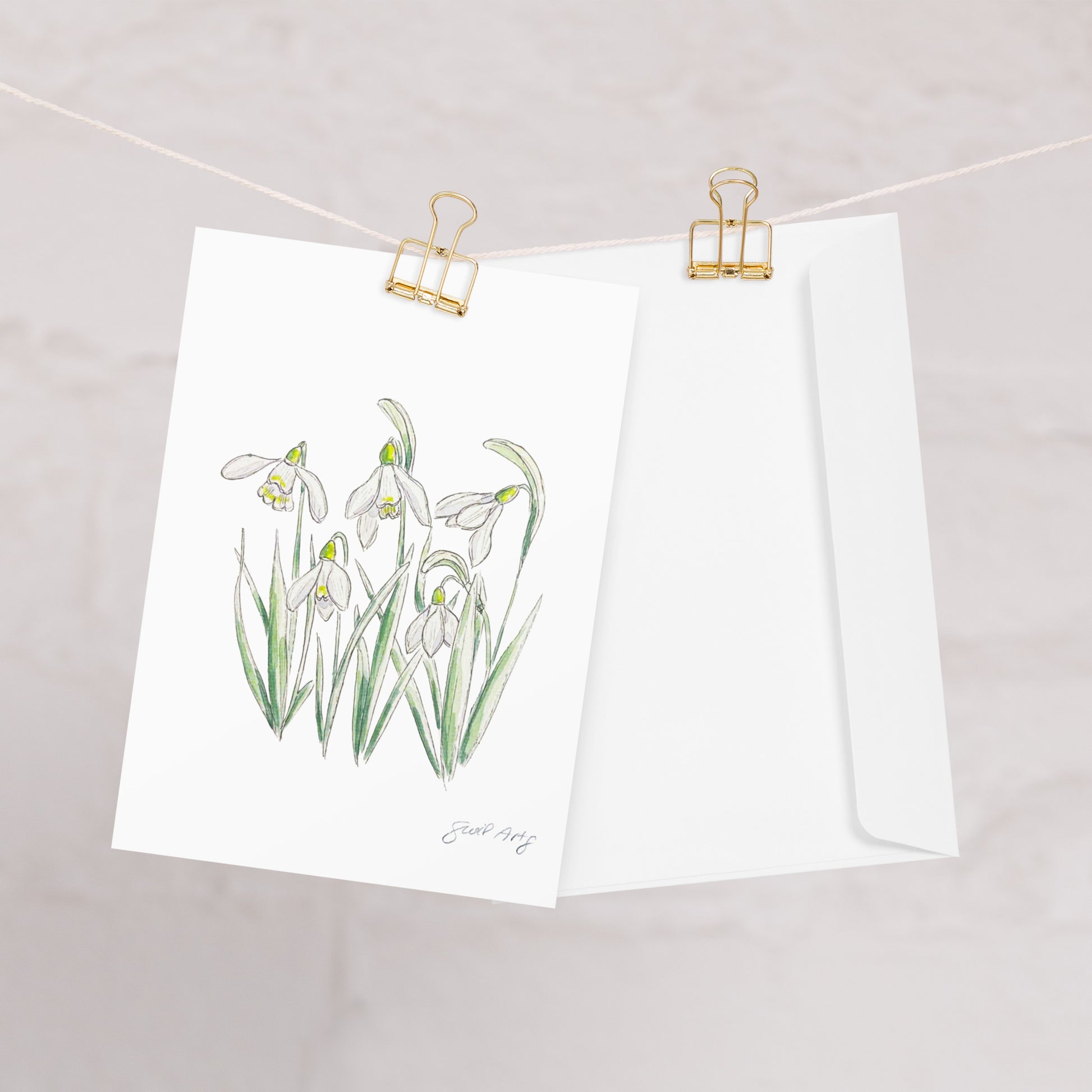 Snowdrop flower greeting card with a watercolor and ink botanical illustration, clipped to a string with a gold binder clip. Includes a matching white envelope. Perfect for nature lovers, special occasions, and handwritten notes.