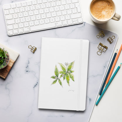 White hardcover notebook with a starflower illustration by Swil Arts, placed on a marble desk with a keyboard, coffee, pencils, and gold binder clips. Aesthetic stationery for journaling, writing, and sketching.