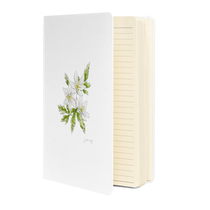 White hardcover notebook featuring a delicate wood anemone flower illustration by Swil Arts. This botanical watercolor and ink design showcases the beauty of nature, making it perfect for journaling, sketching, or note-taking. The notebook includes an elastic closure for convenience, ideal for artists, writers, and nature lovers seeking elegant stationery with a floral touch