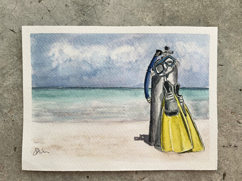 Watercolor painting of a diver on a beach with ocean and sky in the background.