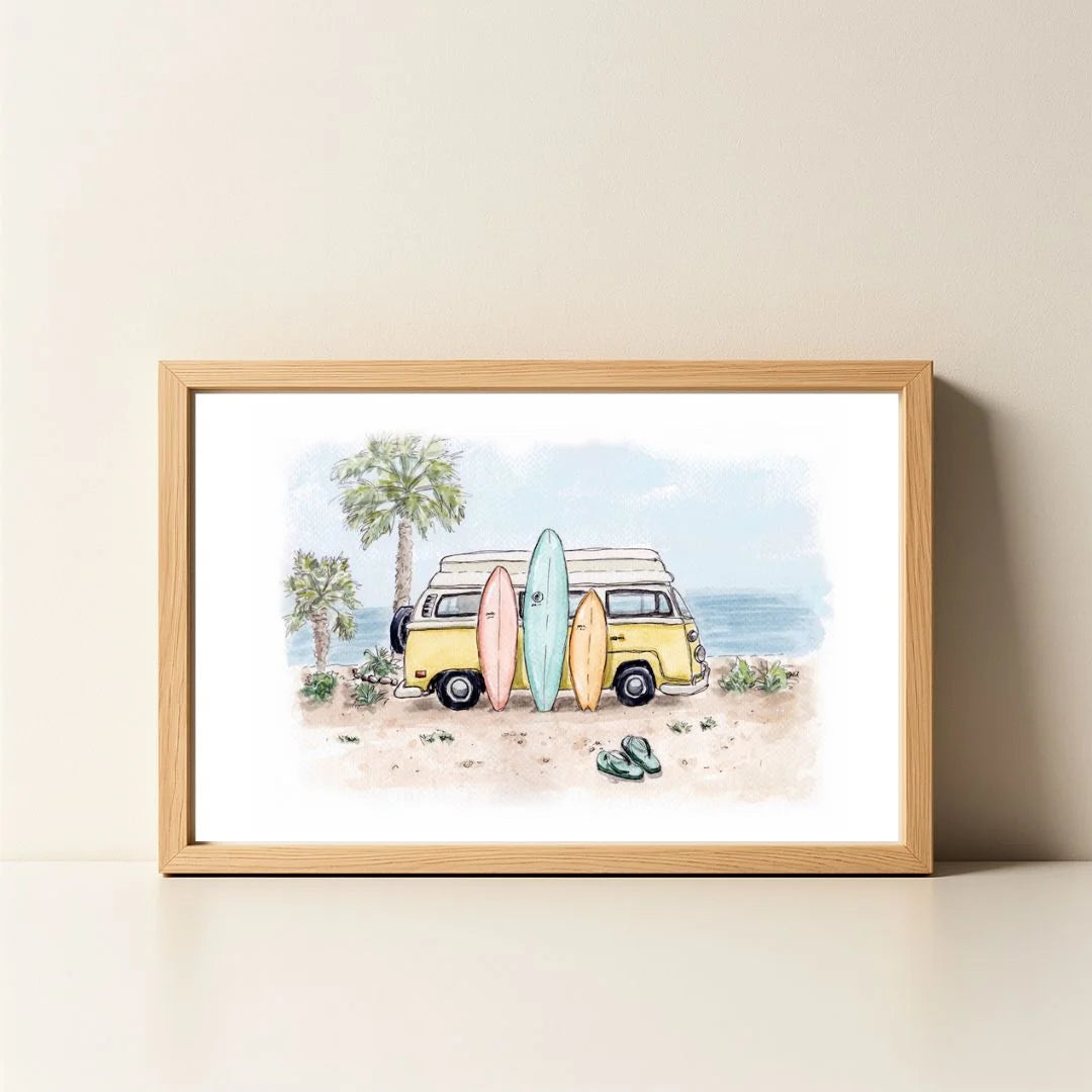 A framed watercolor art print depicting a yellow retro camper van parked on a sandy beach with surfboards, palm trees, and the ocean, displayed on a light beige surface against a neutral wall. Artwork by Sara from Swil Arts
